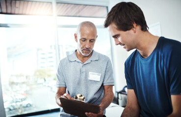 Men, physiotherapist and clinic with patient for rehabilitation with clipboard for checklist, results and report. People, healthcare and smile on fitness, exercise and workout for wellness and happy