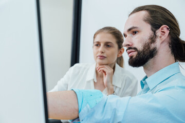 Obraz premium young man and woman colleagues discussing work in office setting. modern workplace with computer and tablet. business meeting and collaboration concept.