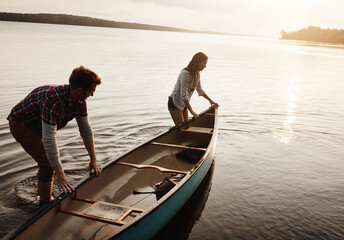 Boat, adventure and man with woman by lake for travel, summer and sunset in nature. Friend or couple and sunshine for happiness, together and freedom or support for canoe and peace by river or creek