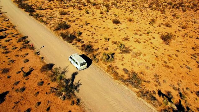 Aerial: Drone Forward Shot Of Van Moving On Road In Semi Arid Desert During Sunny Day - Joshua Tree, California