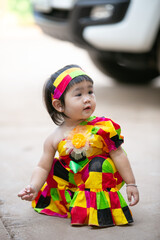 A portrait of a young Asian girl wearing a colorful dress and a festive hat, smiling happily cute little asian 

