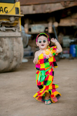 A portrait of a young Asian girl wearing a colorful dress and a festive hat, smiling happily cute little asian 

