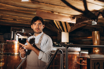 Waist up portrait of bearded brewmaster holding beer glass while inspecting quality of production at brewing factory, copy space