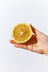 Hand holding a half of an orange on a white background, with the other half in the palm