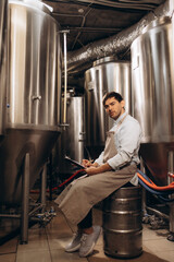A young bearded brewer monitors the sensor readings during the brewing process. Making beer.