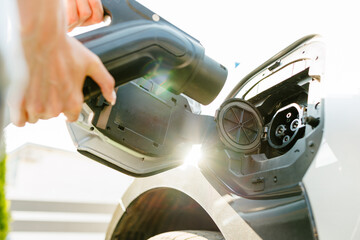 a girl charges her electric car at a charging station, Environmentally friendly energy sources