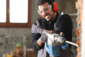 Construction worker suffering arm ache using rotary hammer