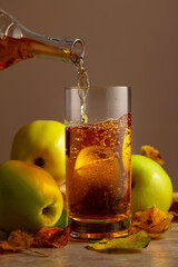 Apple cider is poured from a bottle into a glass.