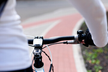 Cyclist riding bike. Road with marking on bicycle path in town. Solo outdoor activity. Woman doing sport. Close up of hands and handlebar. Healthy and sustainable lifestyle. Ecological transportation