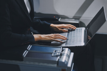 A successful asian businesswoman or female entrepreneur in formal suit in a plane sits in a business class's seat and uses a tablet computer during flight