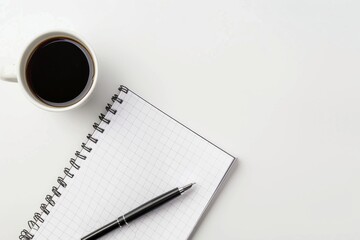 A blank notebook, a pen, and a coffee cup are neatly arranged on a white surface, creating a minimalist workspace