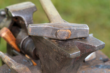 A hammer lies on an anvil, a blacksmith's tool in close-up