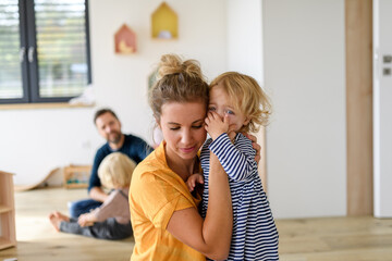Little girl crying and screaming, mother holding her in arms and soothing her.