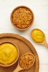 Dijon mustard with french mustard on white wooden background. Vertical photo