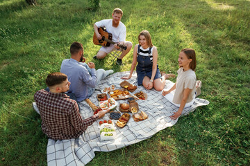 Positive mood, having fun. Group of friends are having picnic on the field with food in eco boxes