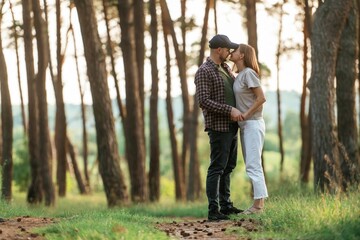 Fototapeta premium Looking at each other. Lovely couple are together in the forest at summer daytime
