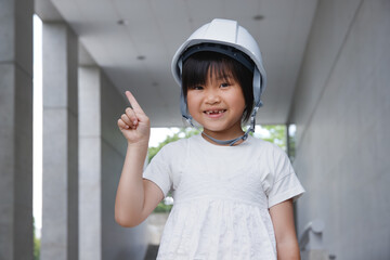 ヘルメットをかぶった笑顔の小学生。指差しポーズで説明イメージ
