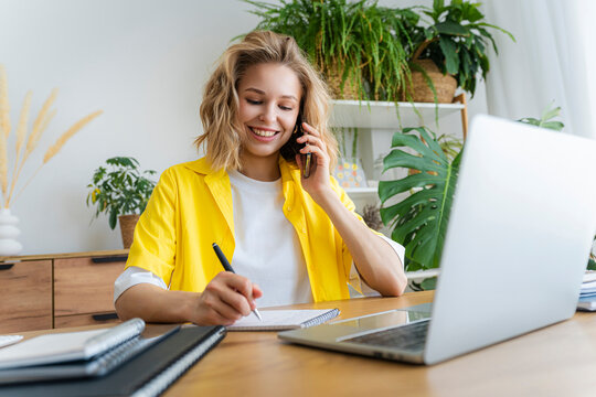 Smiling freelancer doing multi-tasking sitting at desk in home office
