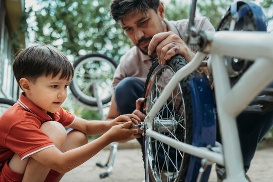 Boy learning to repairing bicycle with father
