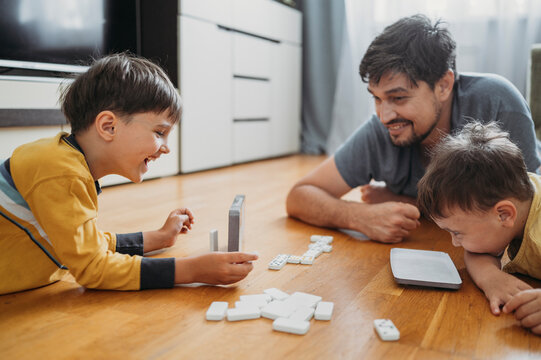 Happy father and children playing dominoes at home