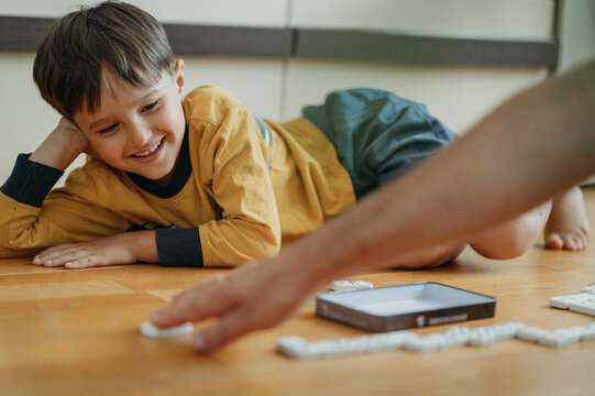 Happy son playing dominoes with father at home