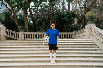 Smiling soccer player holding soccer ball standing on steps