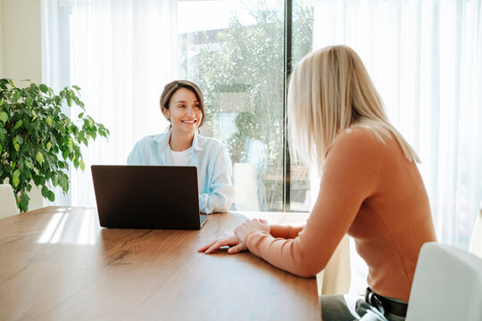Smiling businesswoman with laptop looking at blond colleague