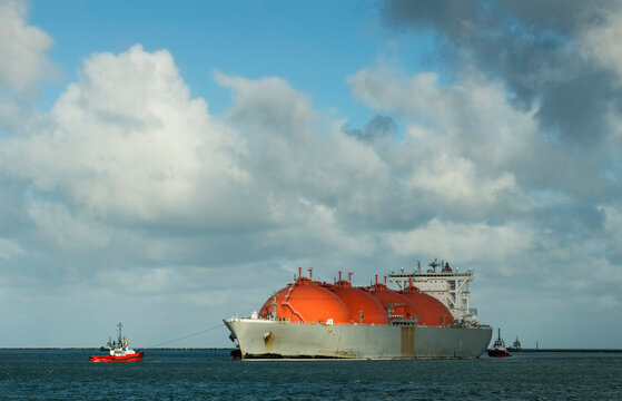 LNG tanker ship arriving at Rotterdam harbor under cloudy sky in Netherlands