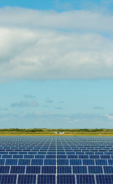 Solar panels in row at field on sunny day under cloudy sky