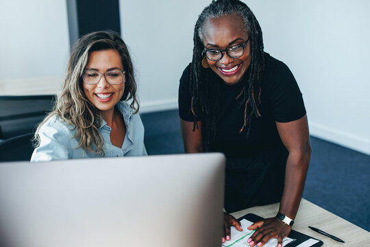 Two business women using a computer to get their work done in an office