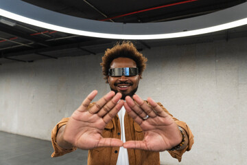 Smiling man wearing smart glasses gesturing in illuminated parking garage