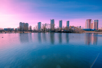 Kyiv in the morning. Left bank of the Dnieper River. Beautiful reflection of buildings in the lake