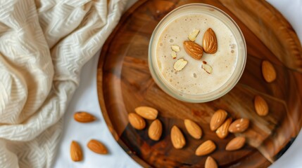 Top view, Almond milk smoothie topped with nuts and grains on a wooden plate, decorated with white flowers