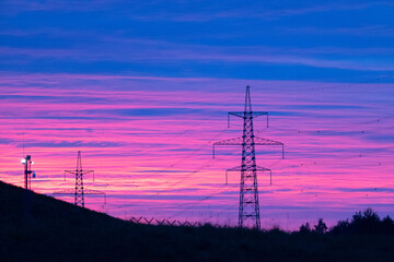 Silhouetted High Voltage Towers Against a Stunningly Vibrant Pink and Purple Sunset Sky