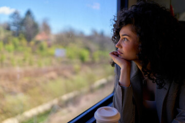 Contemplative woman enjoying the solitude of her train journey, looking out the window with a wistful expression.