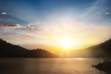 Scenic view of beautiful sunset or sunrise above the pond or lake at spring or early summer evening with cloudy sky background