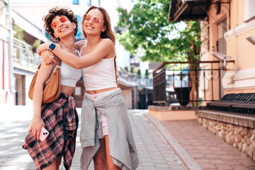 Fototapeta premium Two young beautiful smiling hipster female in trendy summer white t-shirt and shorts clothes. Sexy carefree women posing in the street. Positive models having fun, hugging and going crazy