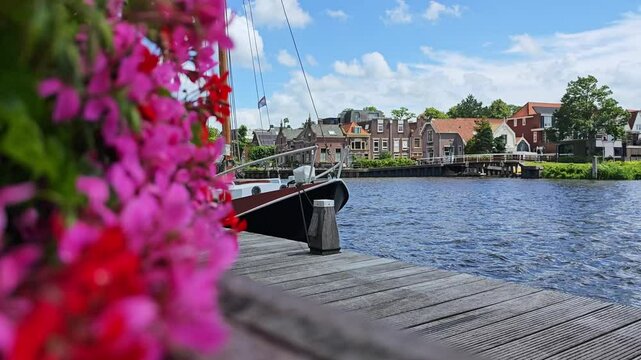 Windy day in Alkmaar, netherlands. A boat on the water, flowers and houses.