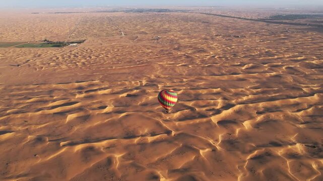 Drone flies around balloons with tourists over the sand dunes of the desert in Dubai