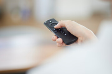 リビングにて動画配信サービスを楽しむ日本人女性の手元とリモコン