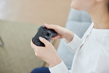 リビングにてオンラインゲームを楽しむ日本人女性の手元とコントローラー