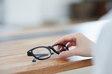 リビングにて老眼鏡を手に取る日本人女性の手元