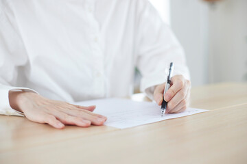 リビングの机にて書類にサインをする日本人女性