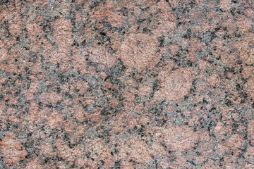 Granite texture. Natural pink granite with a grainy pattern. Stone background. Solid rough surface of rock. Durable construction and decoration material. Close-up.