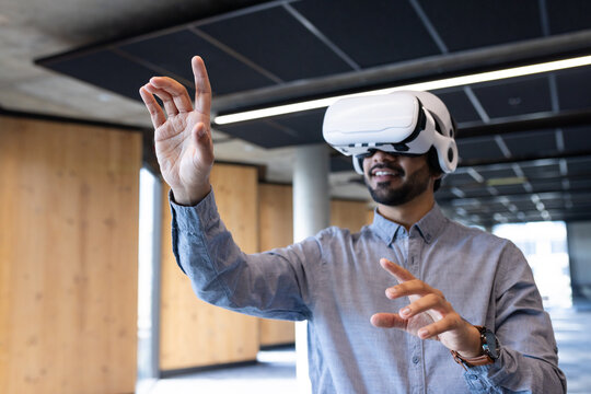 Using VR headset, man interacting with virtual environment in modern office