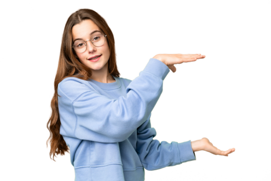 Teenager girl over isolated chroma key background holding copyspace to insert an ad