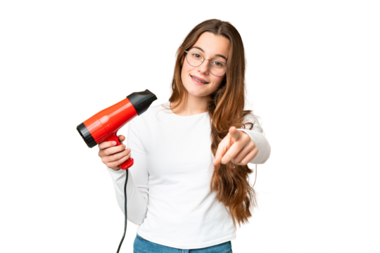 Teenager girl holding a hairdryer over isolated chroma key background points finger at you with a confident expression