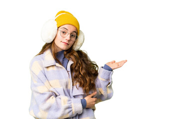 Teenager girl wearing winter muffs over isolated chroma key background extending hands to the side for inviting to come