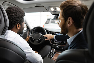 Buyer holds steering wheel while dealer points out vehicle details, showcasing professional service...