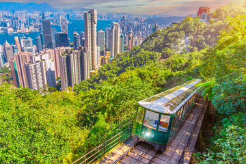 The famous green tram on the slope of Victoria Peak in metropolis Hong Kong passes, lifting up...